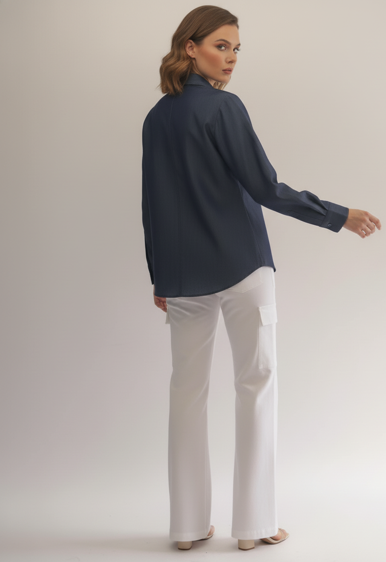 Woman wearing a navy blue shirt and white pants on a plain background
