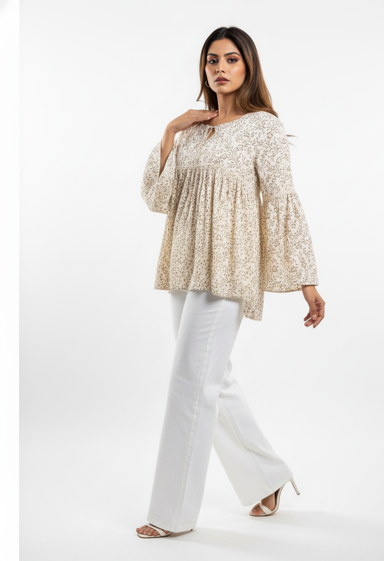 Woman wearing a beige floral blouse and white pants on a white background
