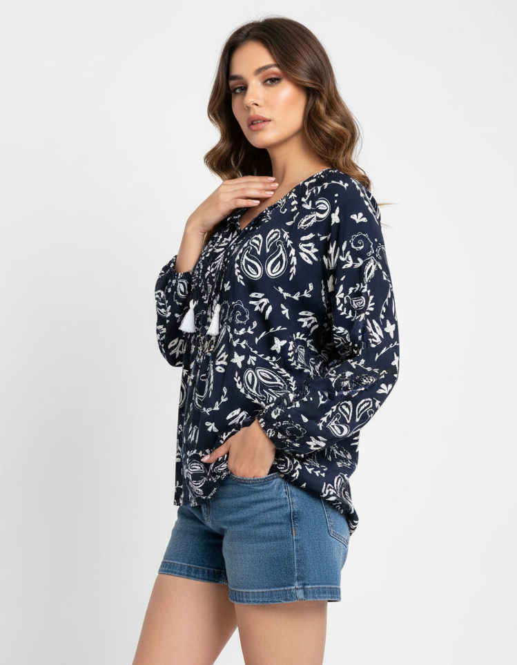 Woman wearing a navy floral patterned top and denim shorts on a white background