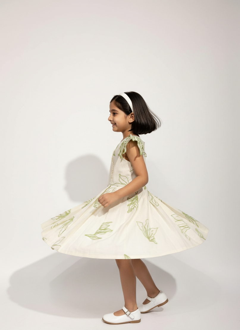 Young girl in a white dress with green floral patterns on a white background