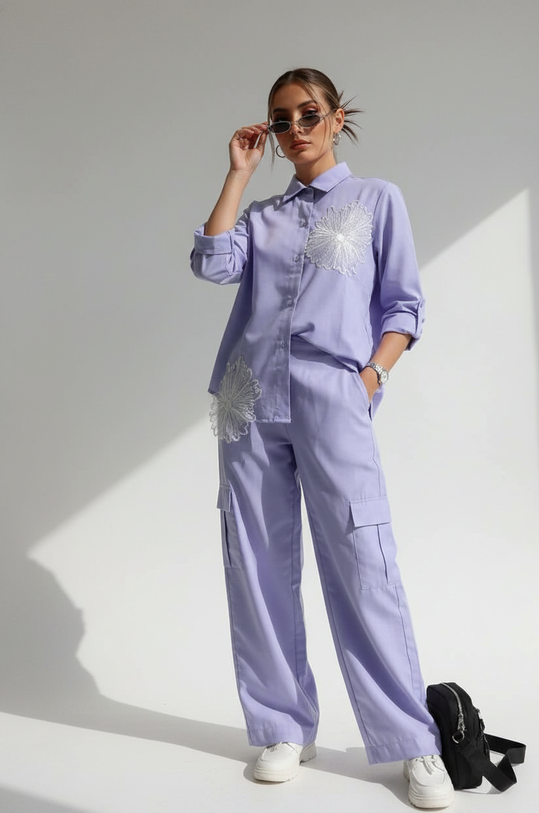 Person wearing a light purple outfit with floral embroidery on a white background