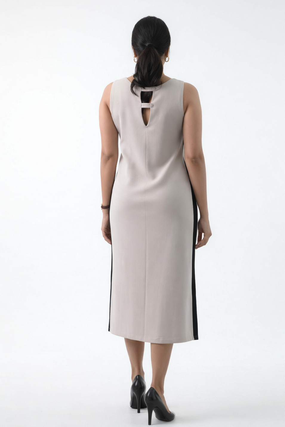 Woman wearing a beige sleeveless dress with a cutout back on a white background