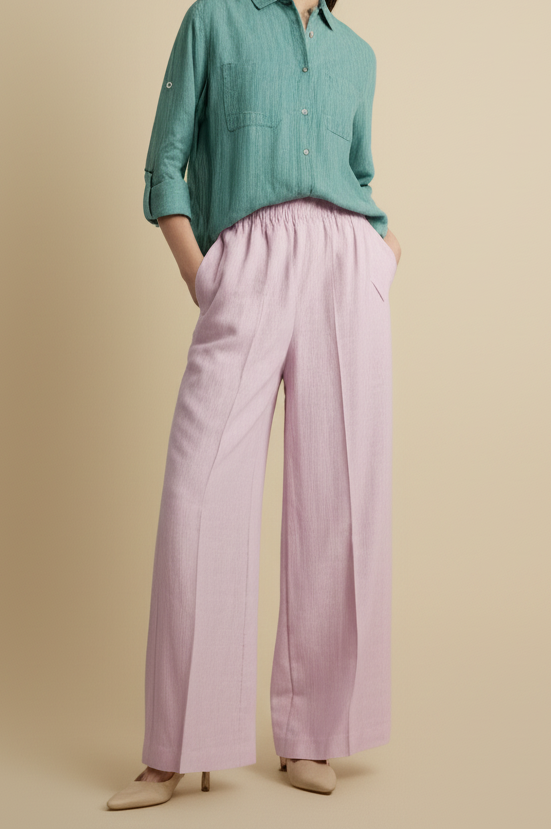 Woman wearing a green shirt and pink pants against a beige background